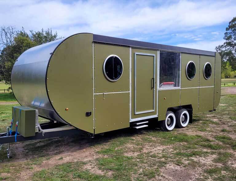 A sleek Hammervan with round windows and a modern design, parked on open grassy grounds at Stawell Grampians Gate C&C Park.