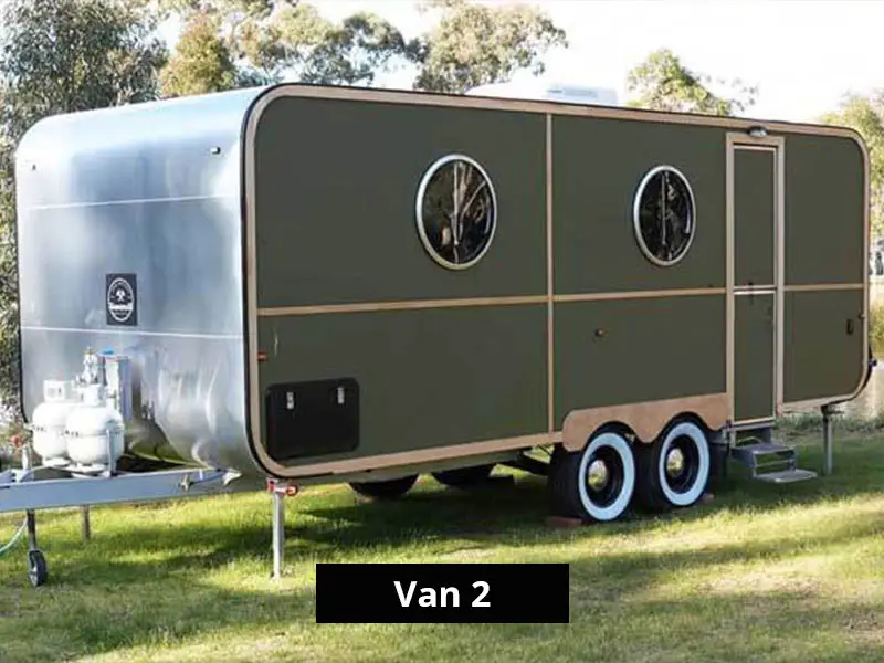 Modern caravan exterior with dual axle, green paneling, round windows and entry steps