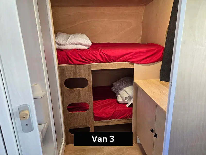 Van bunk beds with timber ladder, red bedding and compact storage space
