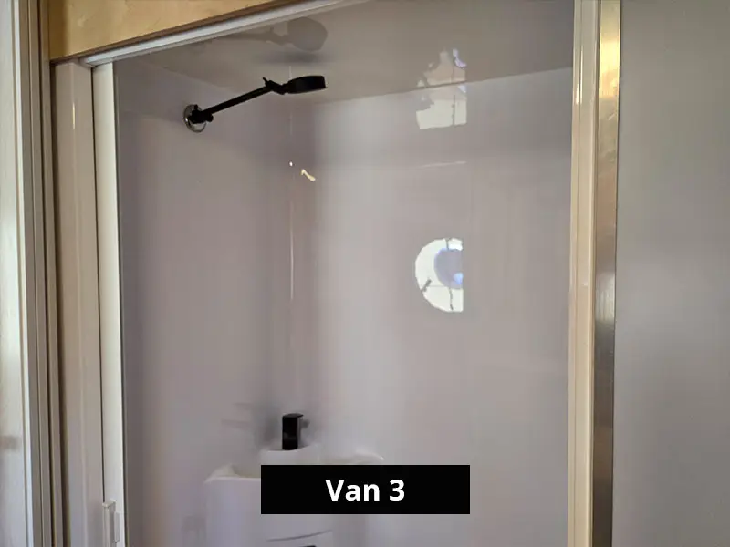 Caravan bathroom with enclosed shower, glass door and wall-mounted shower head