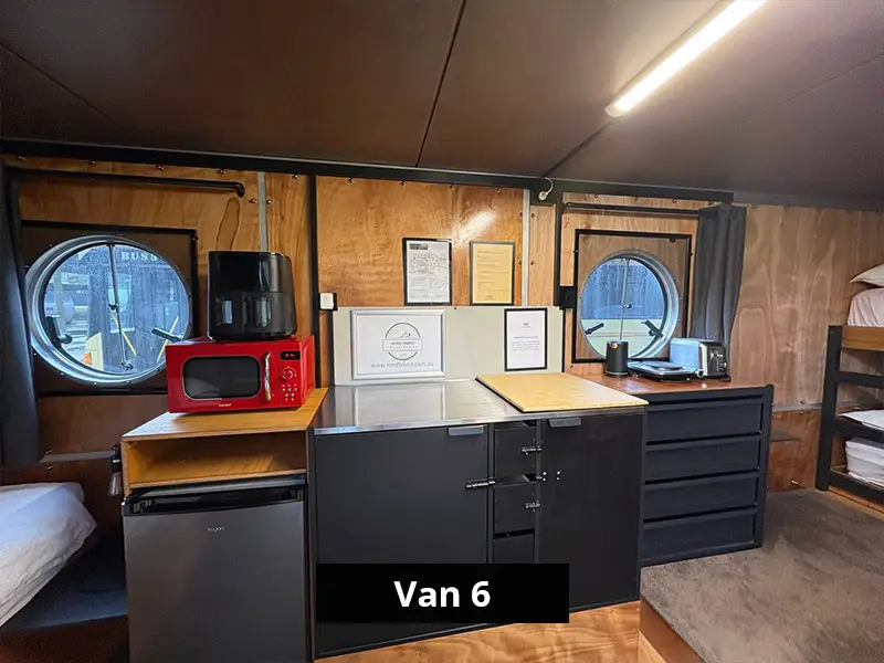 Van kitchenette with microwave, mini fridge, storage cabinets, toaster and round windows
