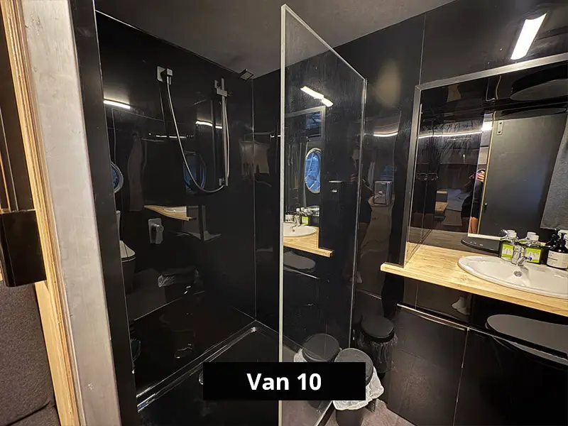 Compact camper van bathroom with glass-enclosed shower, dark modern walls, and sleek fixtures – Van 10