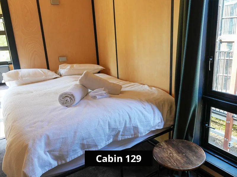 Cabin interior with queen bed, bedside shelving and large windows
