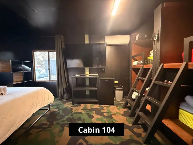 Interior of Cabin 104 at C&V Parks Stawell featuring a queen bed and bunk beds for convenient group and family accommodation.